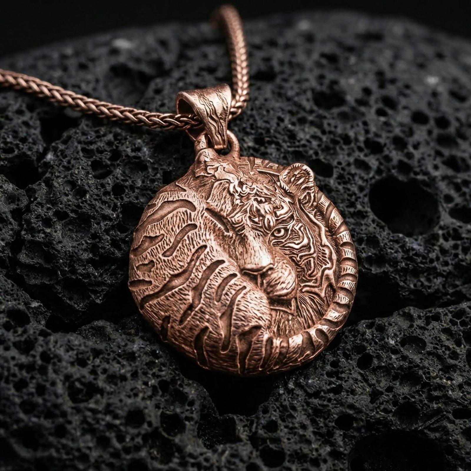 Rose gold plated sleeping tiger necklace with detailed wild cat relief, circular curled body form, and elegant symbolic predator design resting on volcanic rock in an elegant close-up product presentation