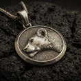 Load image into Gallery viewer, Bronze lioness pendant with detailed feline profile, round medallion frame, and elegant wild cat silhouette displayed on dark volcanic rock in a close-up luxury jewelry composition
