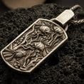Load image into Gallery viewer, Bronze sea life pendant with detailed fish tank scene, swimming fish relief, and elongated rectangular silhouette displayed on dark volcanic rock in a close-up luxury jewelry composition

