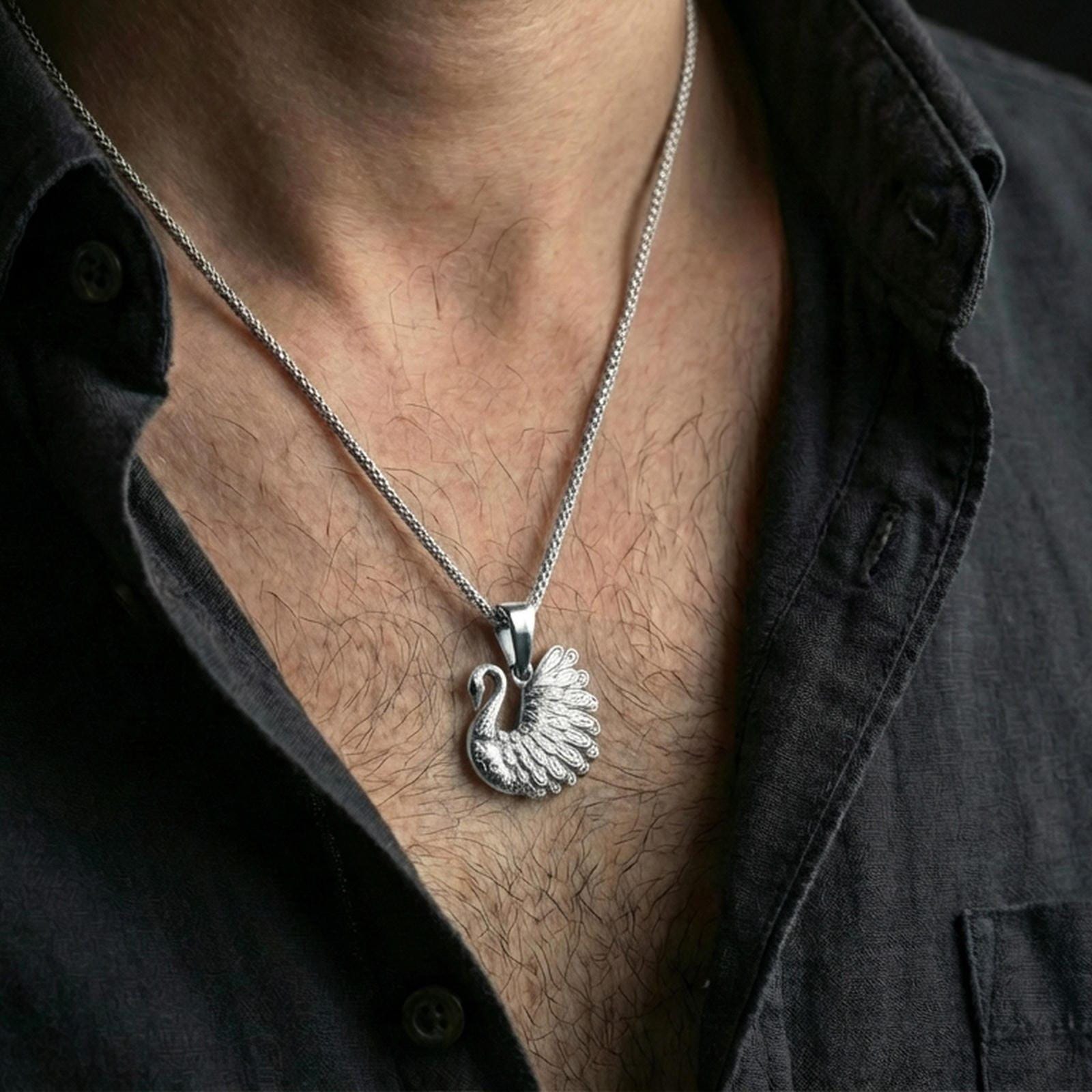 Polished silver swan necklace with layered wing design and graceful bird silhouette worn on the neck in a close lifestyle frame, highlighting the refined feather texture and delicate craftsmanship