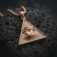 Load image into Gallery viewer, Rose gold plated all-seeing eye pendant necklace on dark volcanic rock, photographed in a detailed premium studio macro view.
