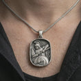 Load image into Gallery viewer, Oxidized Spartan warrior pendant necklace worn on the neck, styled in a dark lifestyle portrait with an open shirt and masculine presentation.
