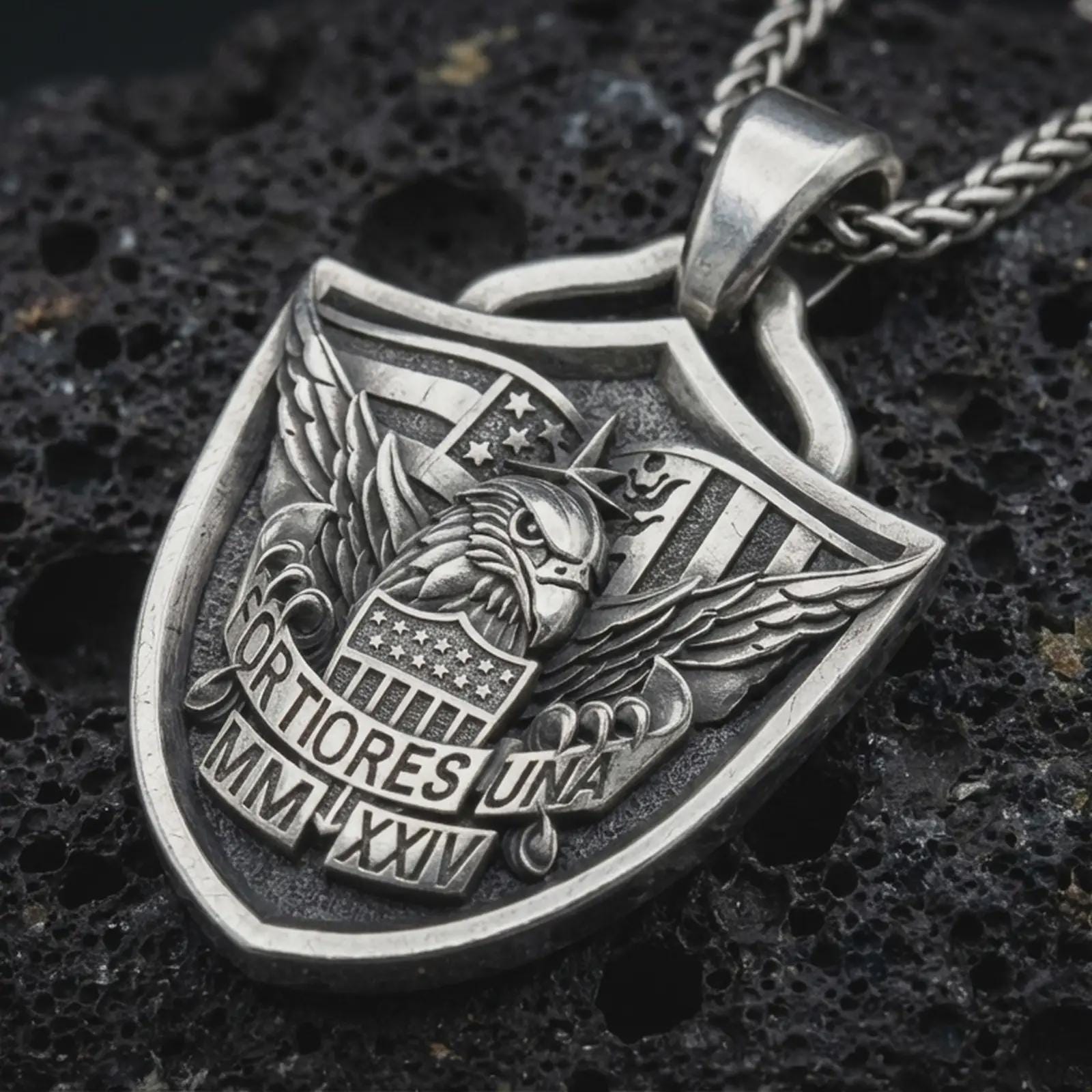 Sterling silver Fortiores Una eagle shield pendant necklace with an oxidized finish resting on textured volcanic rock, captured in a close-up premium studio composition.