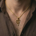 Load image into Gallery viewer, Gold plated Eye of Ra and Ankh pendant necklace worn on the neck, captured on a human model in a premium dark-toned lifestyle frame.
