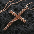 Load image into Gallery viewer, Rose gold plated skull cross pendant necklace on dark volcanic rock, photographed in a detailed premium studio macro view.
