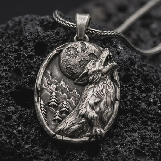 Sterling silver howling wolf pendant necklace with an oxidized finish resting on textured volcanic rock, captured in a close-up premium studio composition.