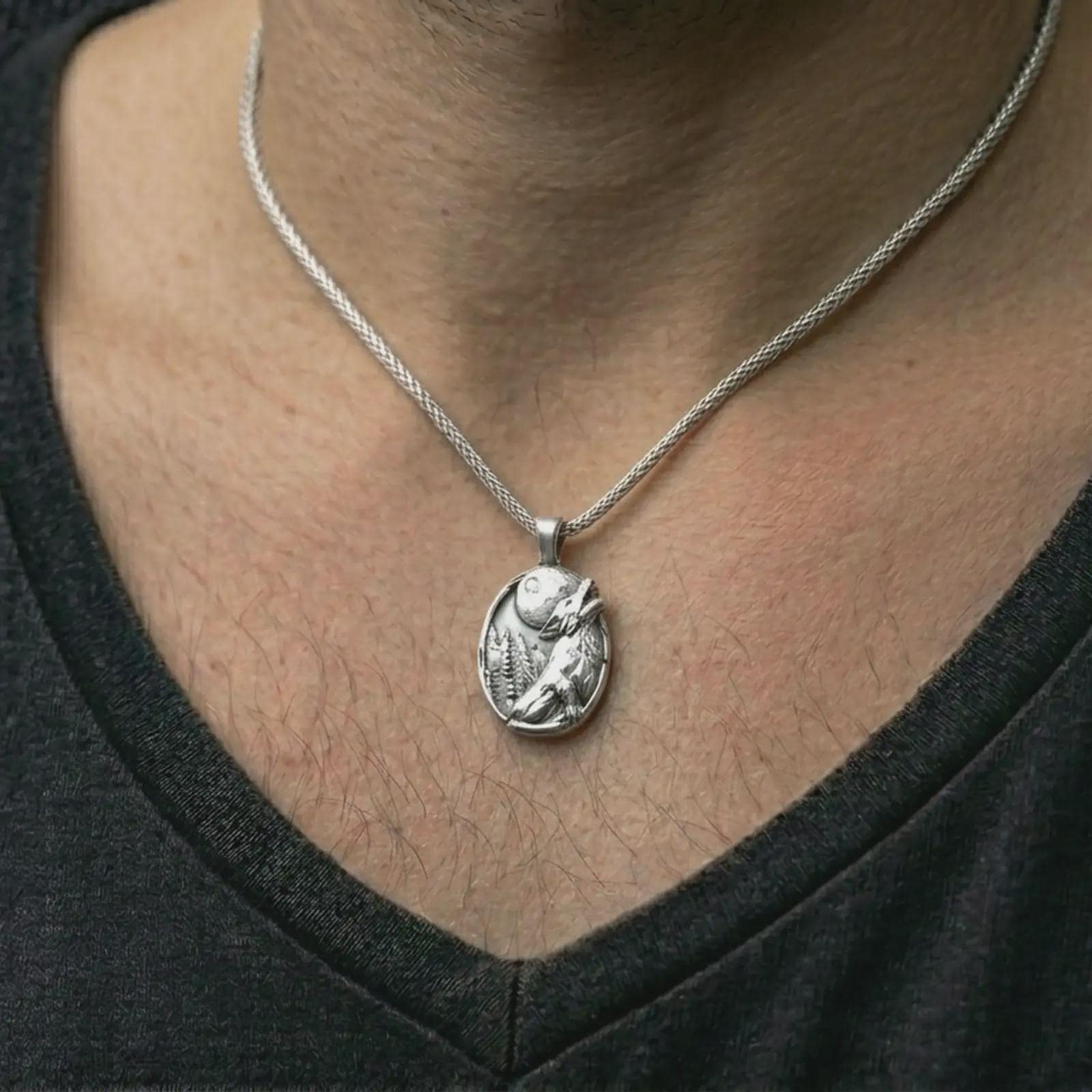 Polished silver howling wolf pendant necklace worn on the neck, shown against the chest in a clean and elegant everyday wear composition.