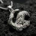 Load image into Gallery viewer, Polished silver Viking raven pendant necklace resting on black volcanic rock, captured in a refined macro product shot with intricate branch details.
