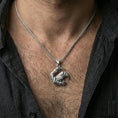 Load image into Gallery viewer, Polished silver Viking raven pendant necklace worn on the neck, shown against the chest in a clean and refined everyday wear composition.
