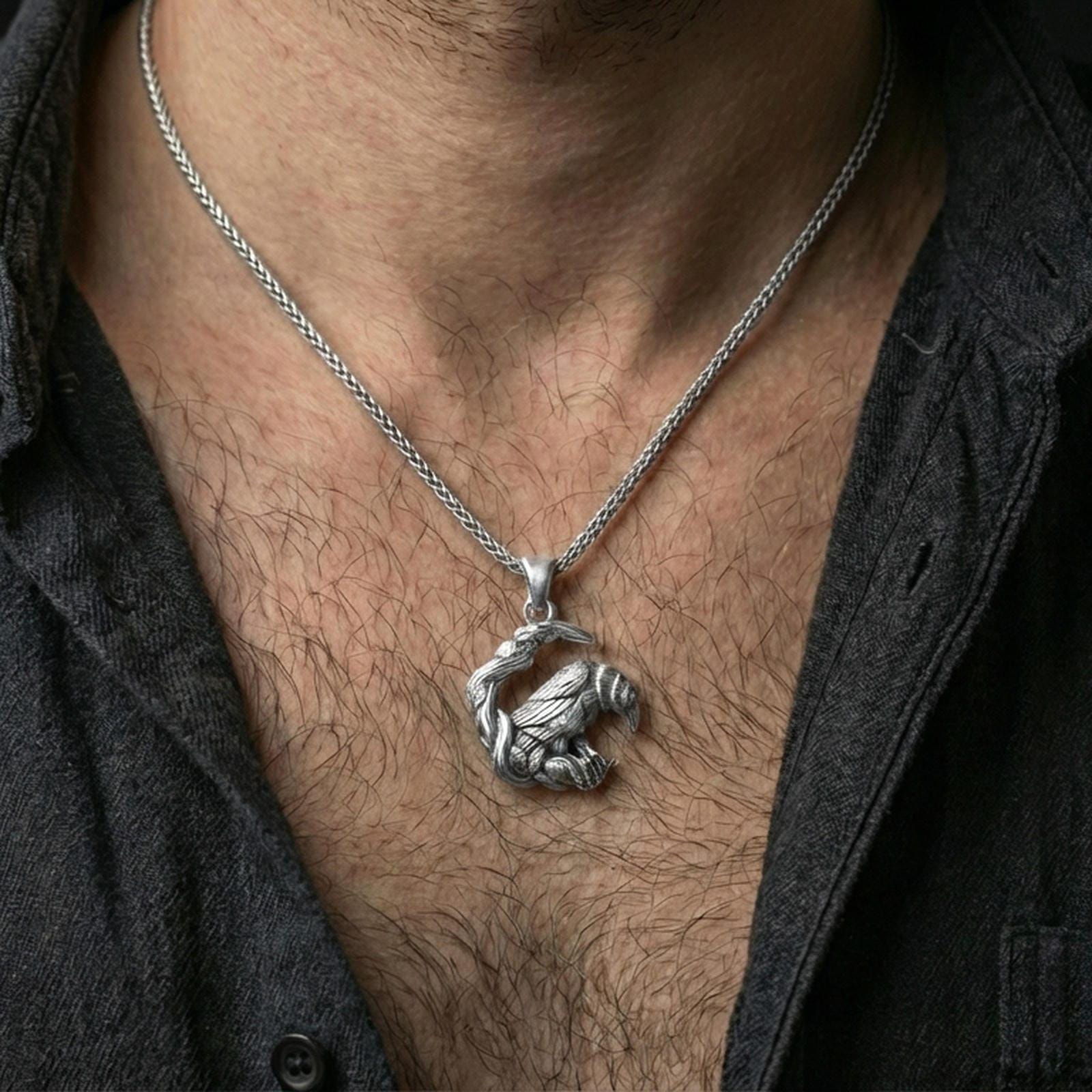 Polished silver Viking raven pendant necklace worn on the neck, shown against the chest in a clean and refined everyday wear composition.