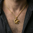 Load image into Gallery viewer, Gold plated Viking raven pendant necklace worn on the neck, captured on a human model in a premium dark-toned lifestyle frame.

