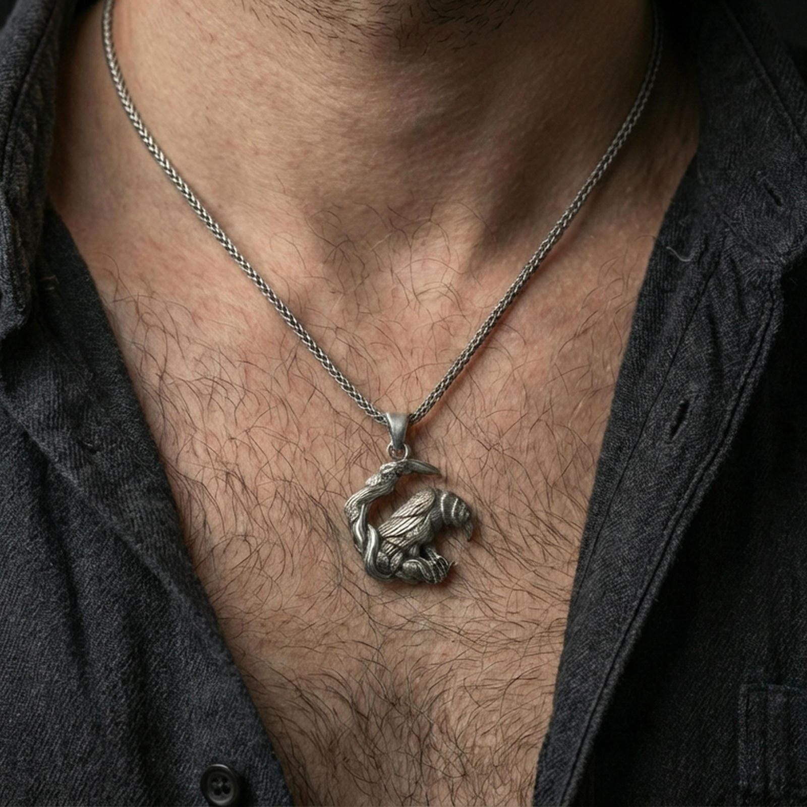 Oxidized Viking raven pendant necklace worn on the neck, styled in a dark lifestyle shot with a masculine open-collar look.