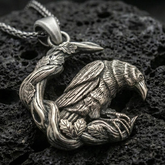 Sterling silver Viking raven pendant necklace with an oxidized finish displayed on textured volcanic rock in a dramatic close-up studio composition.