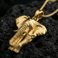 Load image into Gallery viewer, Gold plated elephant pendant necklace presented on porous volcanic rock, highlighting the dimensional animal design in a luxurious close-up jewelry image.
