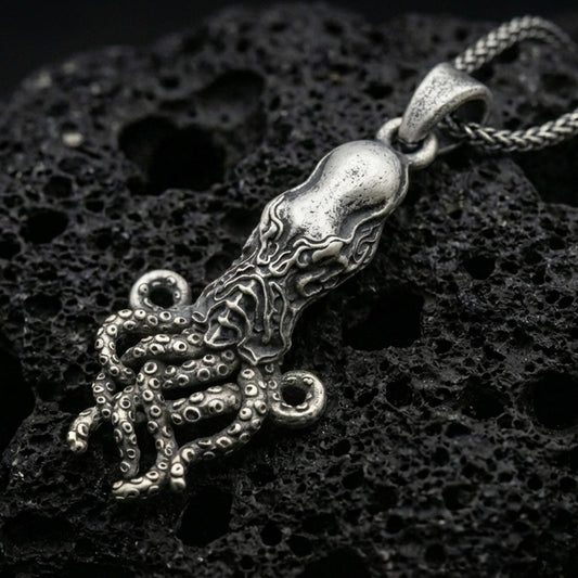Sterling silver octopus pendant necklace with an oxidized finish resting on textured volcanic rock, captured in a close-up premium studio composition.