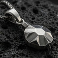 Load image into Gallery viewer, Sterling silver origami tortoise pendant necklace with an oxidized finish resting on textured volcanic rock, captured in a close-up premium studio composition.
