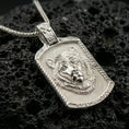 Load image into Gallery viewer, Polished silver bear pendant necklace displayed on black volcanic rock, shown in a refined macro product shot with raised animal relief and textured background detail.
