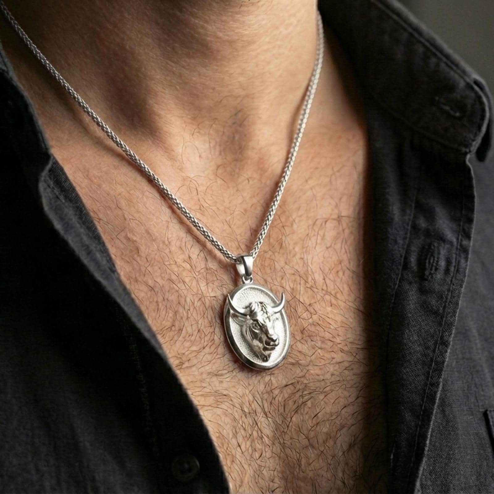 Polished silver bull pendant necklace worn on the neck, shown against the chest in a clean and elegant everyday wear composition.