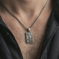 Load image into Gallery viewer, Oxidized mermaid pendant necklace worn on the neck, styled in a dark lifestyle portrait with an open shirt and masculine presentation.
