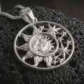 Load image into Gallery viewer, Polished silver sun and moon pendant necklace displayed on black volcanic rock, shown in a refined macro product shot with celestial face detail and star relief.
