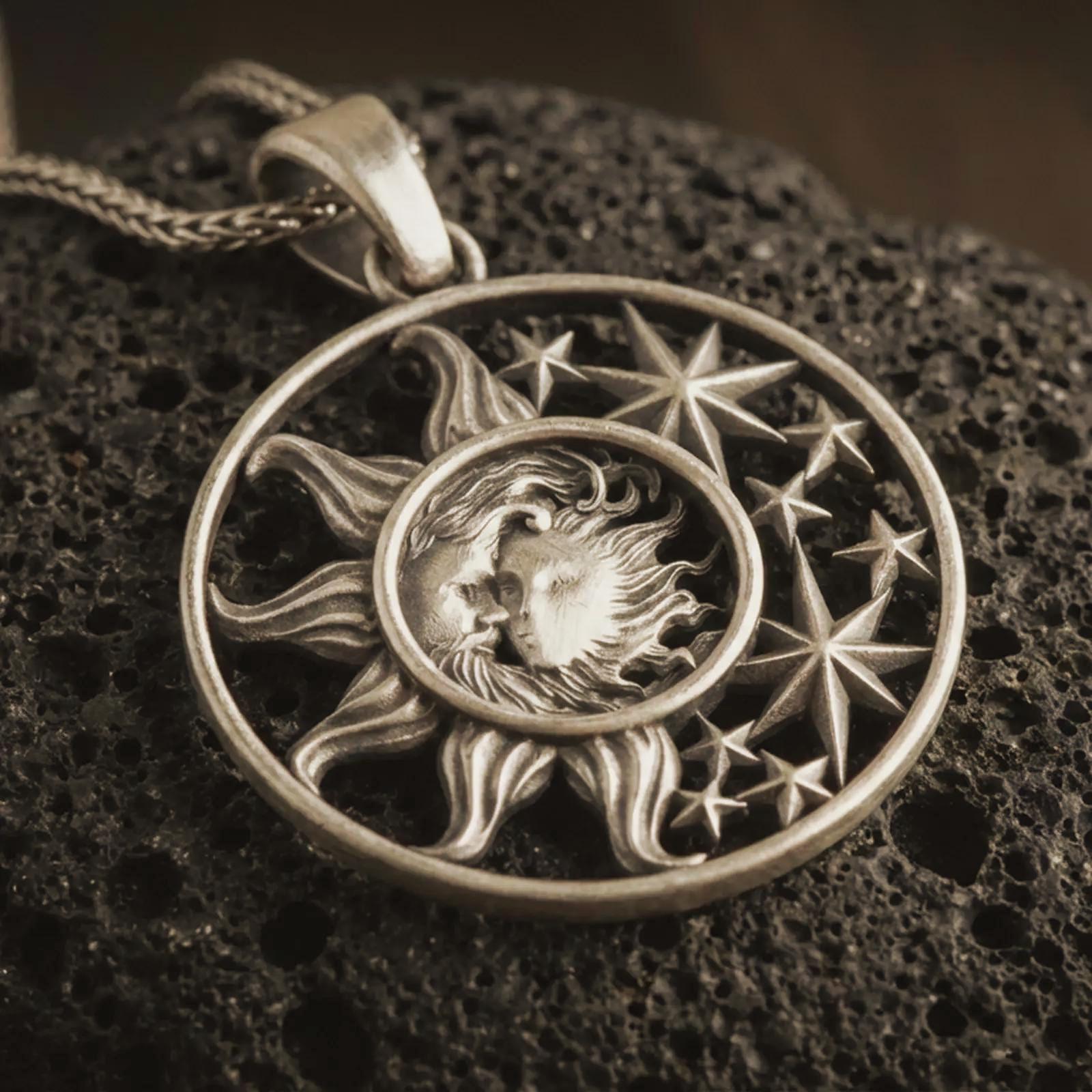 Bronze sun and moon pendant necklace with an oxidized finish resting on textured volcanic rock, captured in a close-up premium studio composition.
