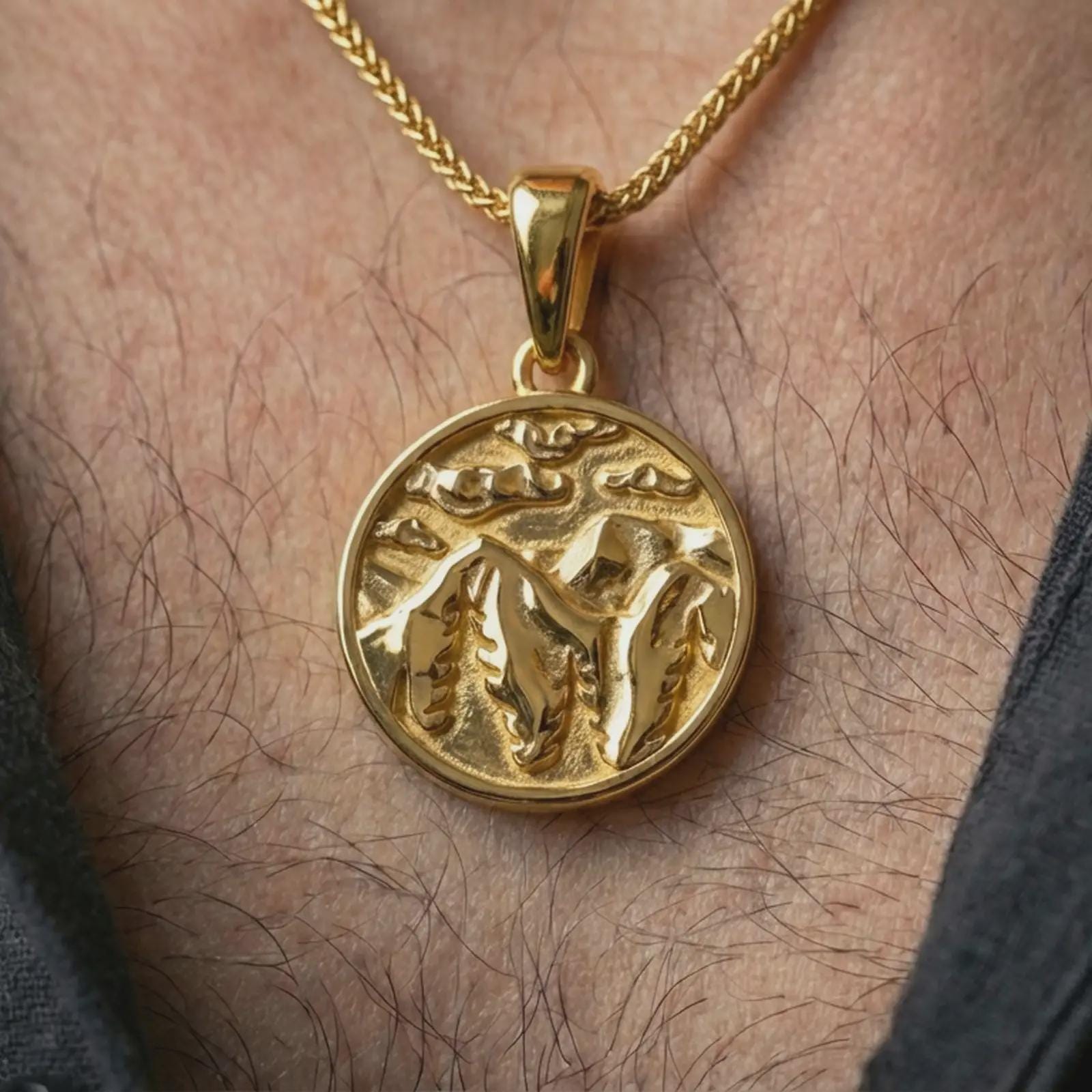 Gold plated mountain landscape pendant necklace worn on the neck, captured on a human model in a premium dark-toned lifestyle frame.