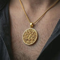 Load image into Gallery viewer, Gold plated Eye of Providence pendant necklace worn on the neck, captured on a human model in a premium dark-toned lifestyle frame.
