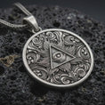 Load image into Gallery viewer, Sterling silver Eye of Providence pendant necklace with an oxidized finish resting on textured volcanic rock, captured in a close-up premium studio composition.
