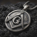 Load image into Gallery viewer, Sterling silver Masonic emblem pendant necklace with an oxidized finish resting on textured volcanic rock, captured in a close-up premium studio composition.
