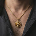 Load image into Gallery viewer, Gold plated Baphomet goat head pendant necklace worn on the neck, captured on a human model in a premium dark-toned lifestyle frame.
