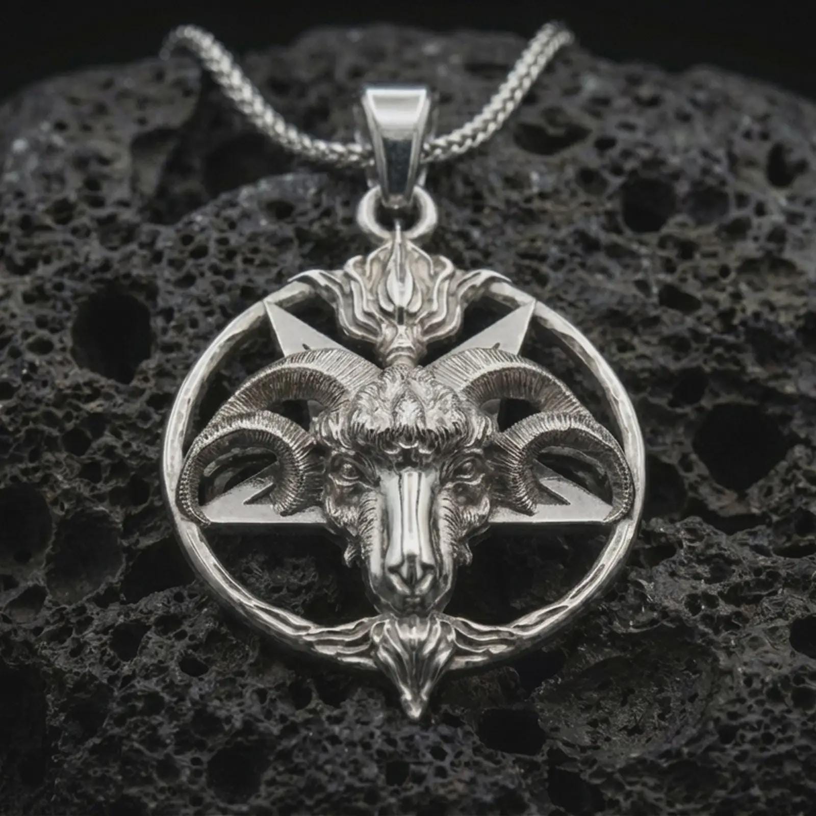 Polished silver Baphomet goat head pendant necklace displayed on black volcanic rock, shown in a refined macro product shot with pentagram frame, ram horns, and occult-inspired relief.