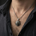 Load image into Gallery viewer, Oxidized tiger lion pendant necklace worn on the neck, styled in a dark lifestyle portrait with an open shirt and masculine presentation.
