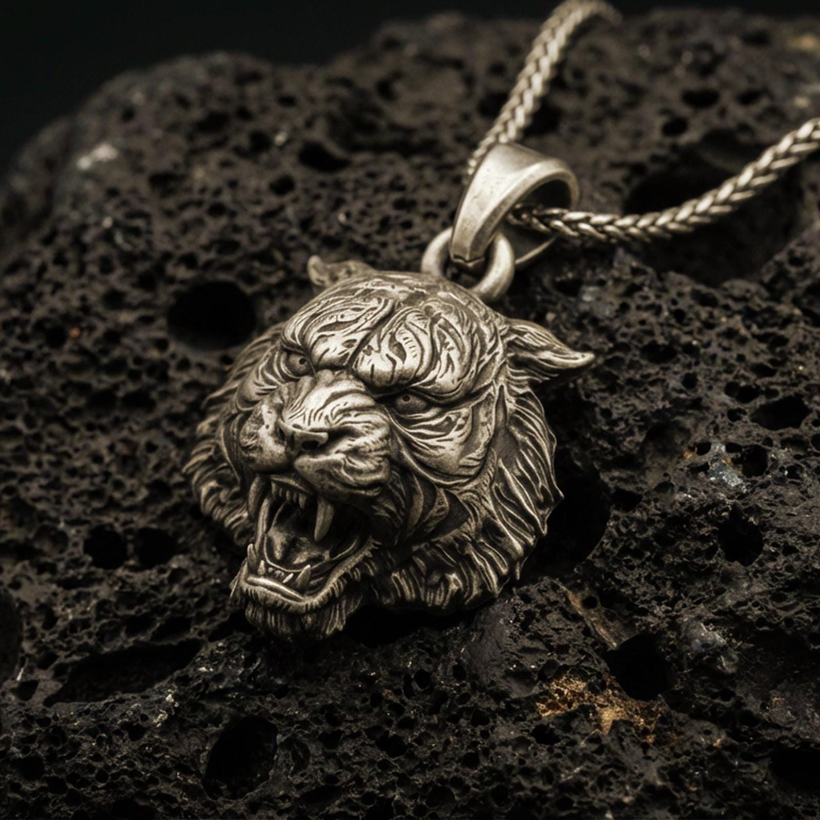 Bronze tiger lion pendant necklace with an oxidized finish resting on textured volcanic rock, captured in a close-up premium studio composition.