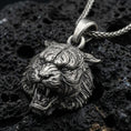 Load image into Gallery viewer, Sterling silver tiger lion pendant necklace with an oxidized finish resting on textured volcanic rock, captured in a close-up premium studio composition.
