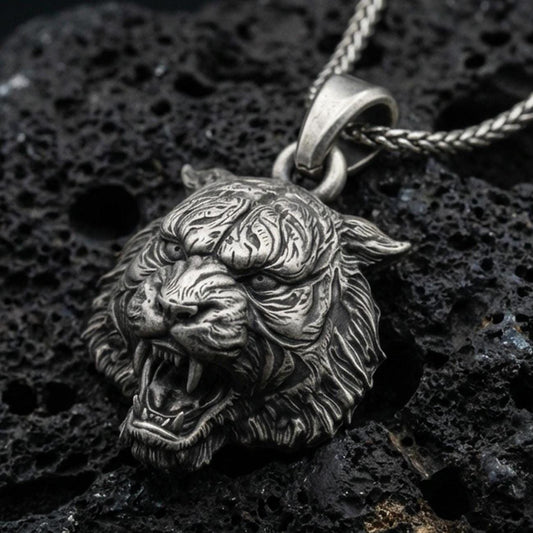 Sterling silver tiger lion pendant necklace with an oxidized finish resting on textured volcanic rock, captured in a close-up premium studio composition.