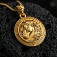 Load image into Gallery viewer, Gold plated horse head medallion necklace presented on porous volcanic rock, highlighting the sculpted equestrian design in a luxurious close-up jewelry image.
