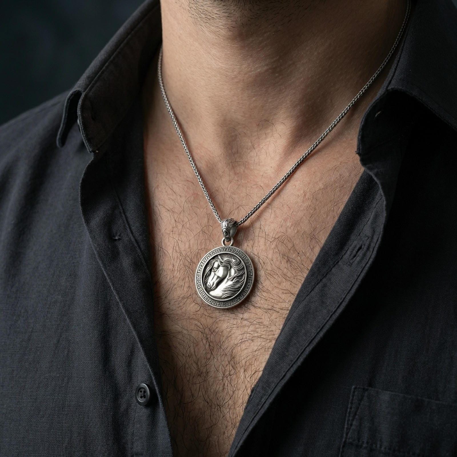 Oxidized horse head pendant necklace worn on the neck, styled in a dark lifestyle portrait with an open shirt and masculine presentation.