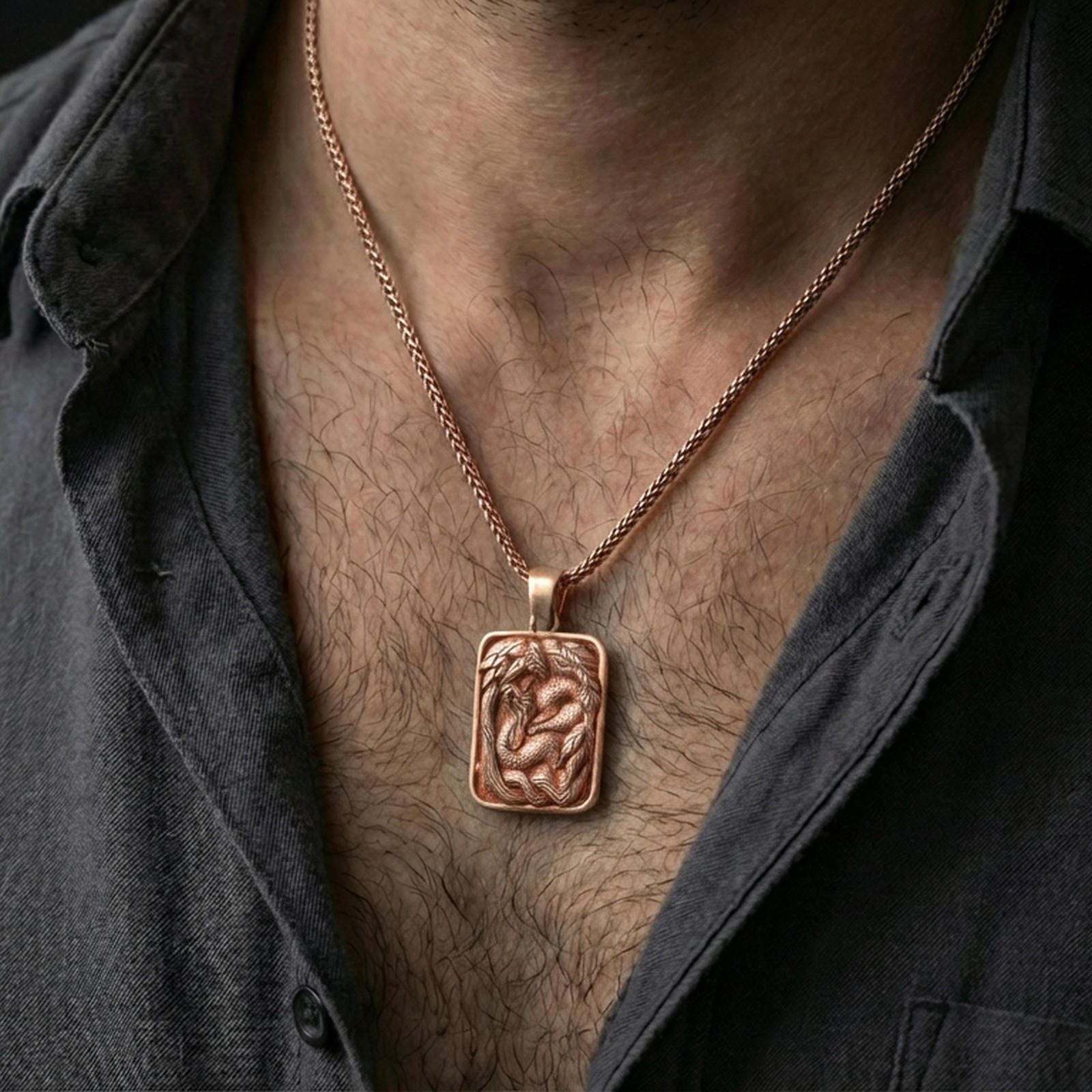 Rose gold plated cobra pendant necklace worn on the neck, presented in a close-up lifestyle shot with a refined masculine aesthetic.