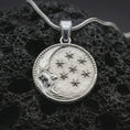 Load image into Gallery viewer, Polished silver moon and stars pendant necklace displayed on black volcanic rock, shown in a refined macro product shot with crescent moon face and celestial star relief.

