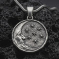 Load image into Gallery viewer, Sterling silver moon and stars pendant necklace with an oxidized finish resting on textured volcanic rock, captured in a close-up premium studio composition.
