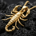 Load image into Gallery viewer, Gold plated scorpion pendant necklace presented on porous volcanic rock, highlighting the sculpted arachnid form in a luxurious close-up jewelry image.
