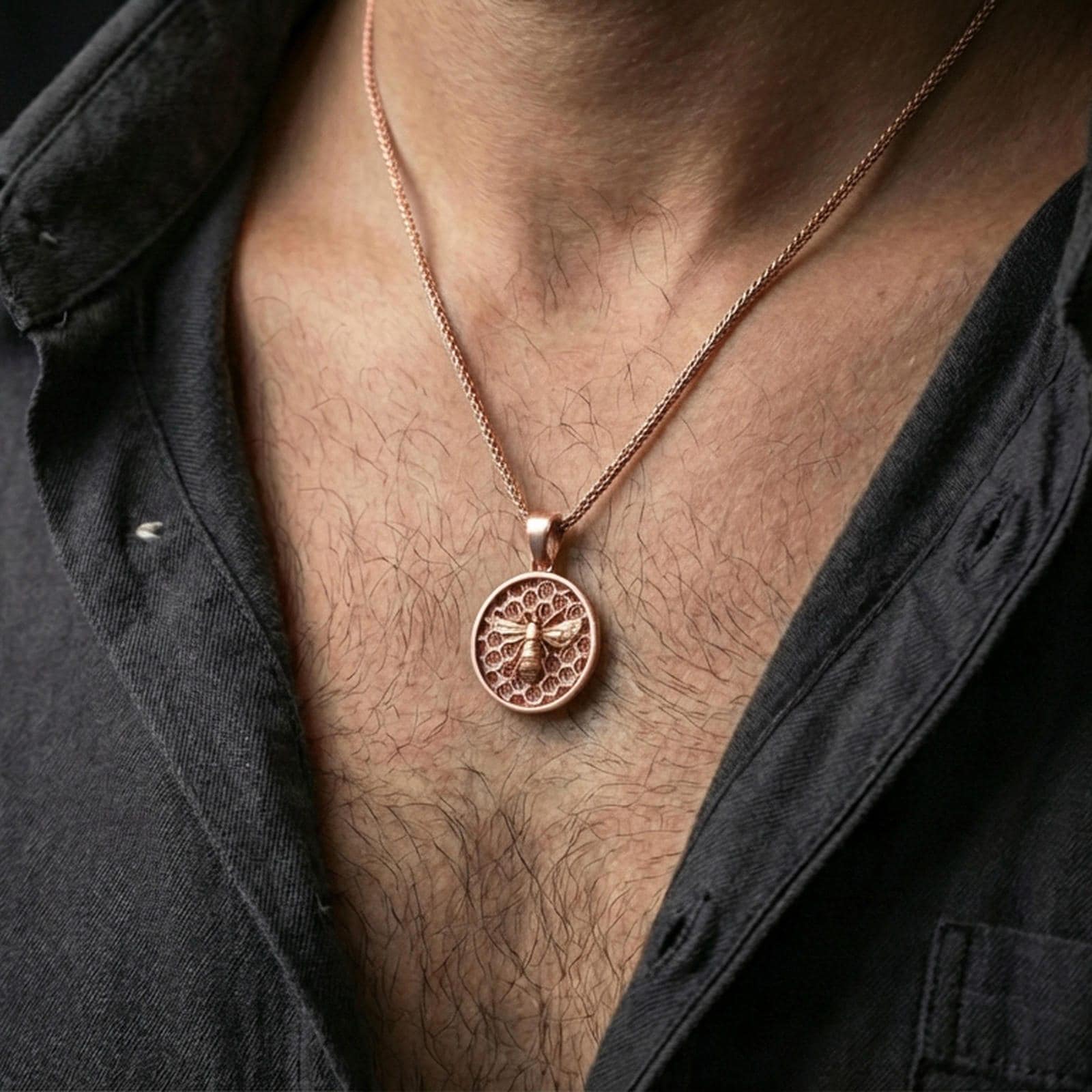 Rose gold plated bee pendant necklace worn on the neck, presented in a close-up lifestyle shot with a refined masculine aesthetic.