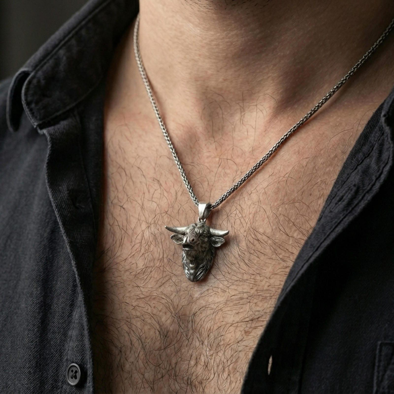 Oxidized buffalo head pendant necklace worn on the neck, styled in a dark lifestyle portrait with an open shirt and masculine presentation.
