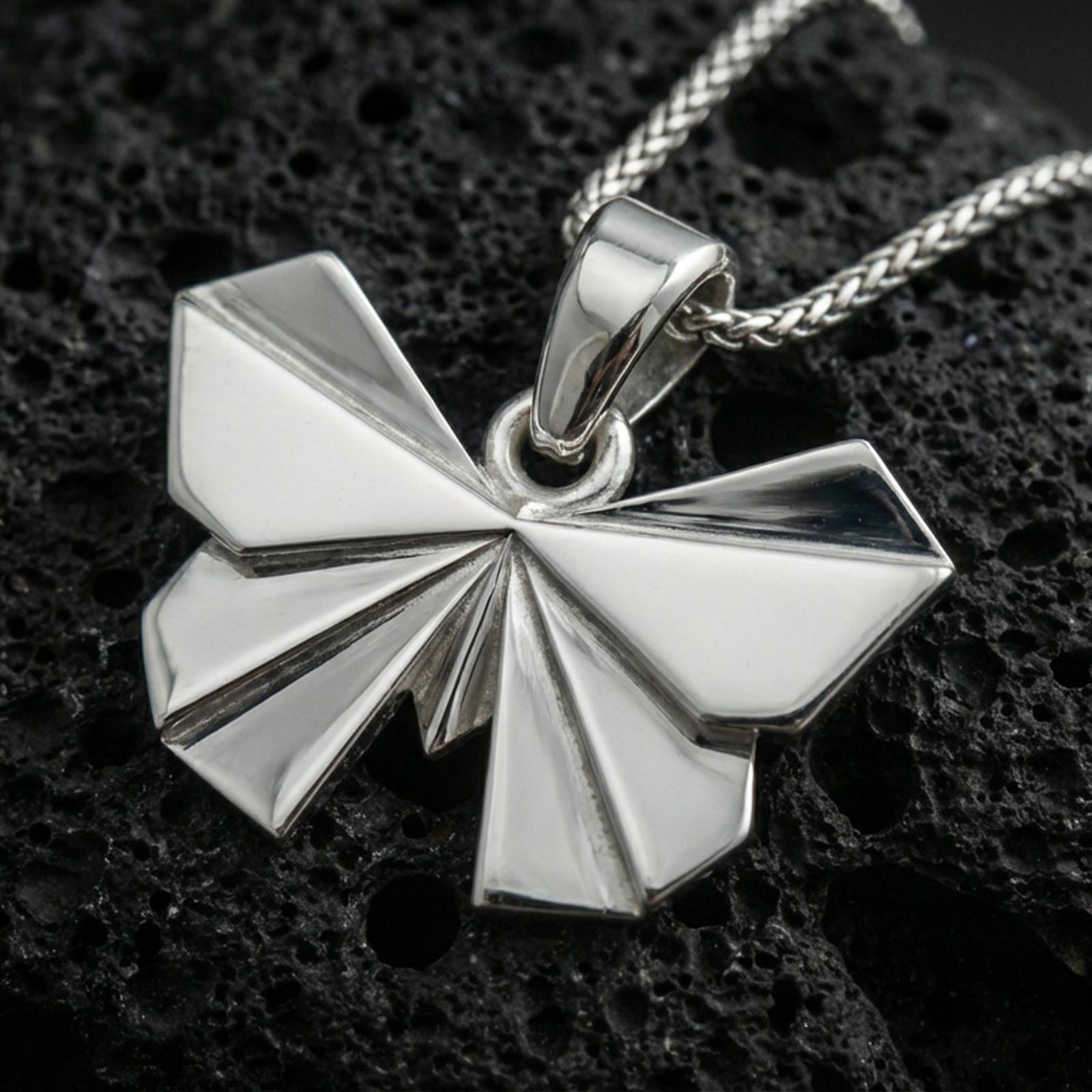 Polished silver origami butterfly pendant necklace displayed on black volcanic rock, shown in a refined macro product shot with sharp folded wing details.