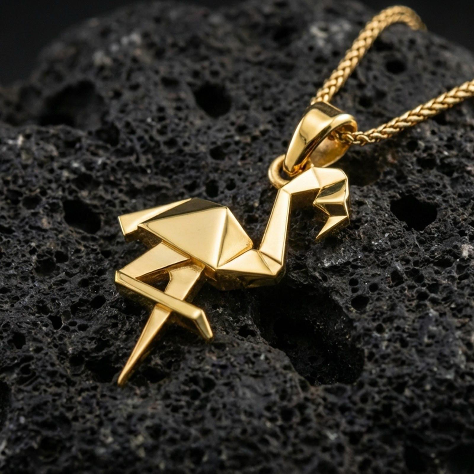 Gold plated origami flamingo pendant necklace presented on porous volcanic rock, highlighting the angular bird silhouette in a luxurious close-up jewelry image.