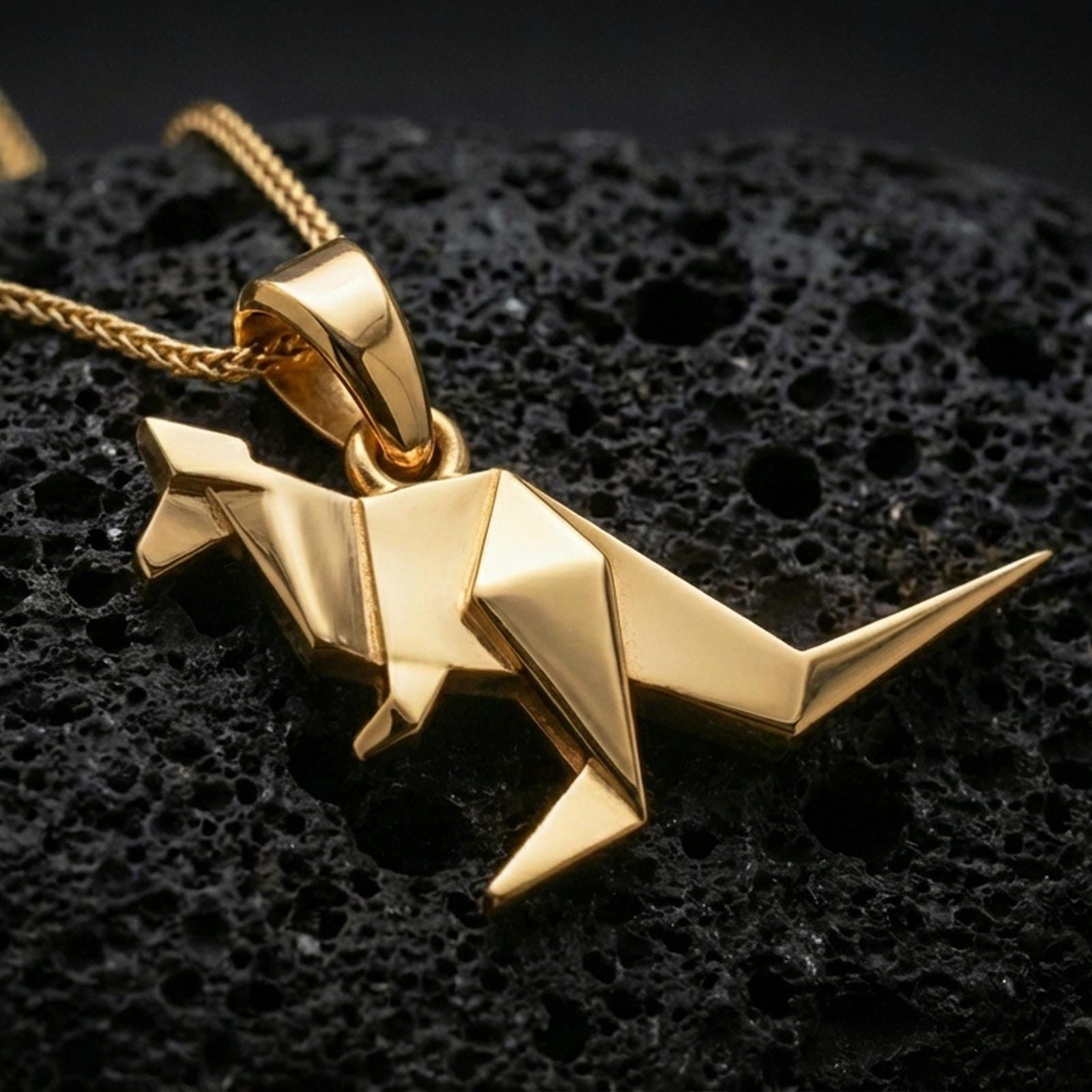 Gold plated origami kangaroo pendant necklace presented on porous volcanic rock, highlighting the angular animal silhouette in a luxurious close-up jewelry image.