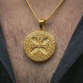 Load image into Gallery viewer, Gold plated Celtic knot medallion necklace worn on the neck, captured on a human model in a premium dark-toned lifestyle frame.
