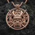 Load image into Gallery viewer, Rose gold plated samurai skull pendant necklace on dark volcanic rock, photographed in a detailed premium studio macro view.
