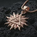 Load image into Gallery viewer, Rose gold plated Eye of Providence sun pendant necklace on dark volcanic rock, photographed in a detailed premium studio macro view.
