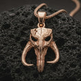Load image into Gallery viewer, Rose gold plated Mythosaur skull pendant necklace on dark volcanic rock, photographed in a detailed premium studio macro view.
